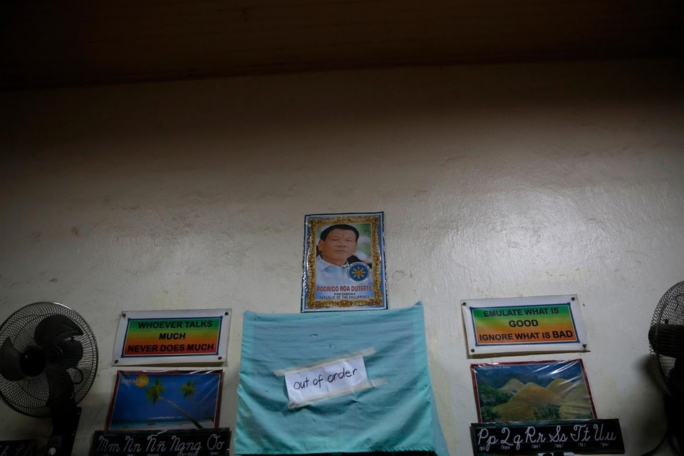 Cuộc sống bên trong trại cai nghiện ma túy ở Philippines - 5 Chân dung Tổng thống Rodrigo Duterte được treo trong một phòng học của các học viên cai nghiện ở thành phố San Fernando. Trên tường cũng treo các khẩu hiệu để giáo dục tư tưởng cho các học viên như “Nói ít làm nhiều” hay “Hãy làm việc tốt, tránh xa việc xấu”.