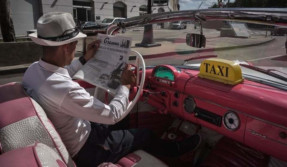 Người dân Cuba nghẹn ngào tưởng nhớ lãnh tụ Fidel Castro - 10 Một tài xế lái taxi đọc tin về ông Fidel Castro đăng trên báo hôm qua 26/11. Tất cả các tờ báo ở Cuba đều được in mực đen, thay vì màu đỏ và xanh da trời như truyền thống, trong những ngày quốc tang. (Ảnh: AFP)