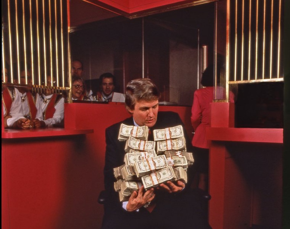 Câu chuyện phía sau những bức chân dung biểu tượng của ông Trump - 3 Bức ảnh do phóng viên ảnh Harry Benson chụp ông Trump ở Atlantic City cho báo People vào năm 1990. “Ngay sau khi sòng bạc Taj Mahal khai trương ở Atlantic City vào năm 1990, tôi đã đến đó để chụp ảnh Donald Trump. Ông ấy nói với tôi rằng có hơn một triệu USD tiền mặt trong két của sòng bạc. Tôi nói với ông ấy rằng tôi chưa được thấy một triệu USD tiền mặt bao giờ. Và thế là ông Trump đi thẳng vào két, lấy ra đúng một triệu USD, ôm vào người để chụp ảnh. Hành động này của ông Trump vào thời điểm đó gây hoang mang cho nhiều người vì theo luật của sòng bạc, không ai được phép mang tiền mặt ra ngoài. Tôi thấy đây là bức ảnh đáng nhớ nhất trong ngày hôm đó”, Harry Benson kể lại.