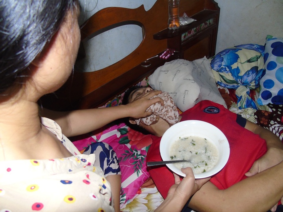 Thương chồng nhưng chị Hà bất lực không thể làm gì hơn ngoài việc cố gắng bón cho chồng từng thìa cháo trong vô vọng.