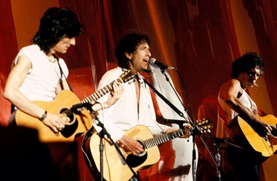 Chân dung nhạc sĩ đầu tiên trong lịch sử đoạt… Nobel Văn học - 21 1985: Bob Dylan (giữa) biểu diễn với hai thành viên Ronnie Wood và Keith Richards của ban nhạc Rolling Stones tại Philadelphia, Mỹ.