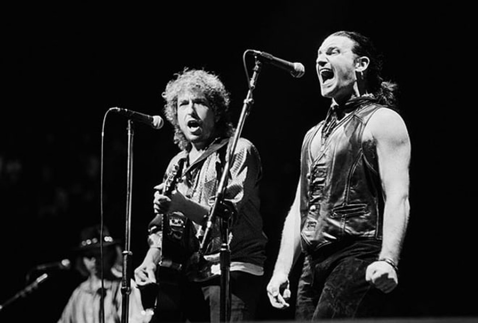 Chân dung nhạc sĩ đầu tiên trong lịch sử đoạt… Nobel Văn học - 23 1987: Bob Dylan biểu diễn với nam ca sĩ Bono - trưởng nhóm nhạc U2 tại Inglewood, California, Mỹ.