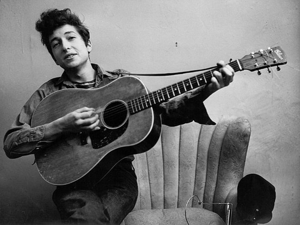 Chân dung nhạc sĩ đầu tiên trong lịch sử đoạt… Nobel Văn học - 3 1963: Bob Dylan và cây ghita gắn liền với hình ảnh của chàng nghệ sĩ lãng tử.