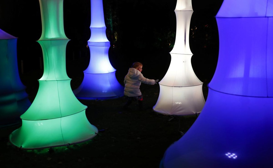 Cô bé vui đùa bên những sắp đặt nghệ thuật ánh sáng nằm trong Vườn thực vật hoàng gia Kew, London, Anh.