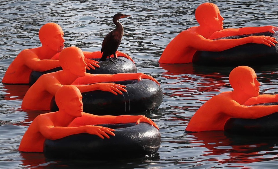 Một chú chim đậu trên sắp đặt nghệ thuật “SOS” đang trưng bày tại eo biển Fort Point, thành phố Boston, Mỹ. Những hình người này tượng trưng cho gần 1 triệu người di cư tị nạn trên khắp thế giới hôm nay - những người đã thực hiện những cuộc hành trình vượt biển nguy hiểm.