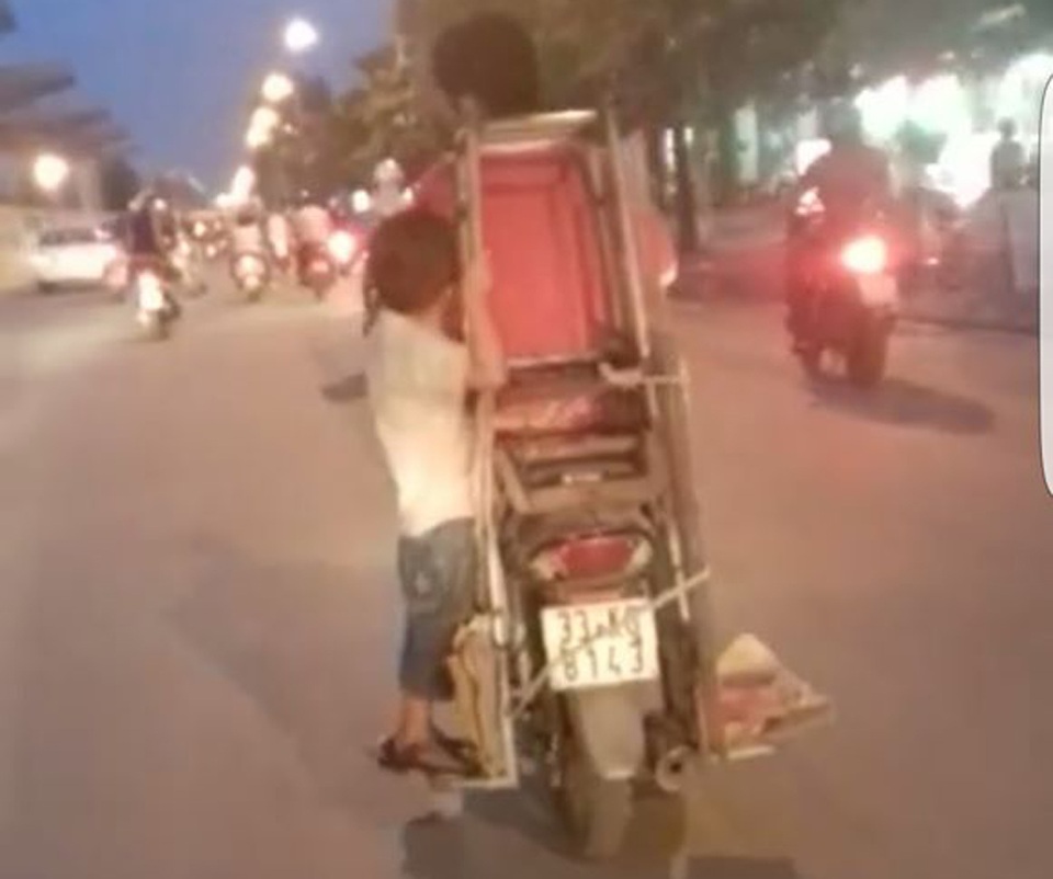 Hà Nội: Rùng mình chứng kiến bé trai “đánh đu” bên xe máy - 1 Hình ảnh bé trai đánh đu trên chiếc xe máy đang lao vun vút trên đường (Ảnh cắt từ clip).