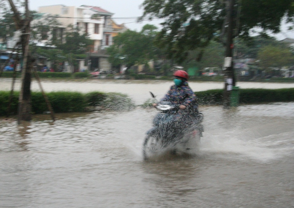 Người dân lái xe xông qua nước lũ