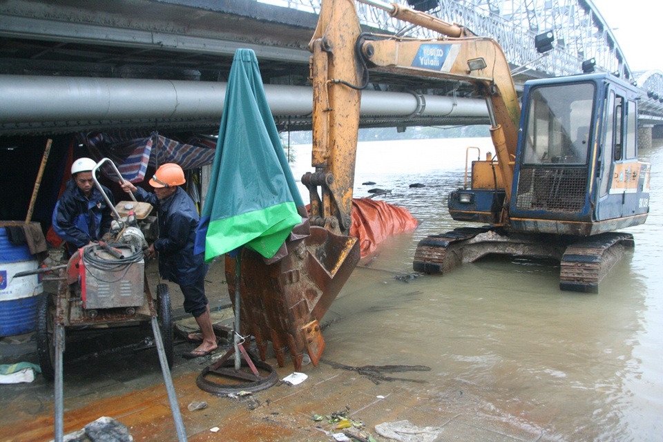 Các công nhân của Dự án cải thiện môi trường nước TP Huế di chuyển vật dụng dưới cầu Trường Tiền tránh lụt