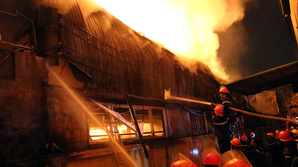 Cảnh sát tiếp cận đám cháy, phun nước dập lửa.