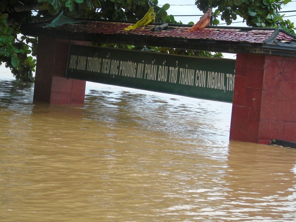 
Nước lũ ngập gần lút cổng trường, không còn thấy bờ tường bao đâu.
