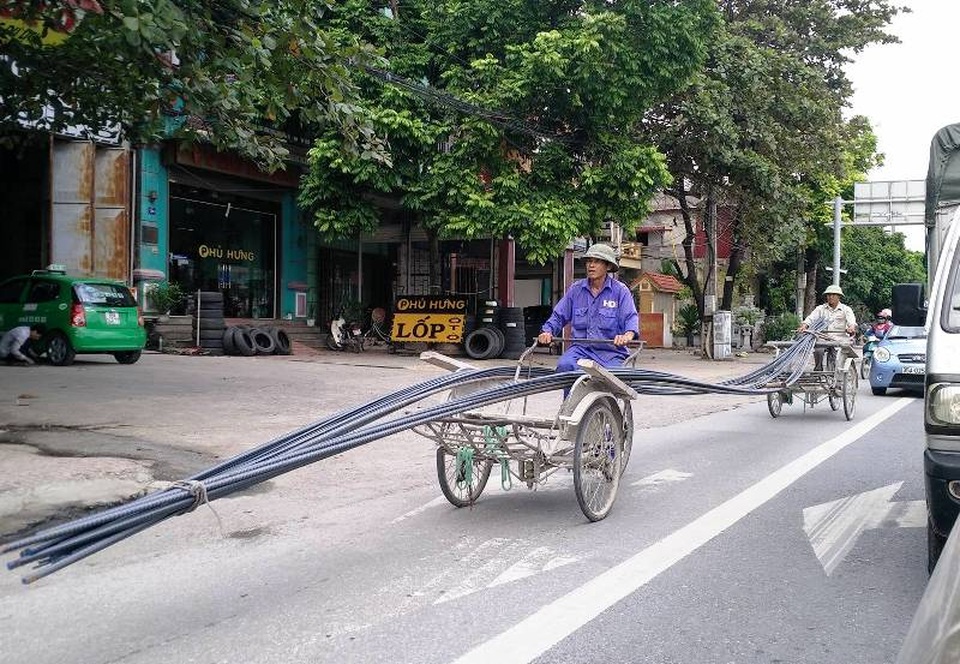 Hai xe xích lô cùng chở rất nhiều cây thép tạo thành chiếc xe siêu dài, siêu tải trọng...