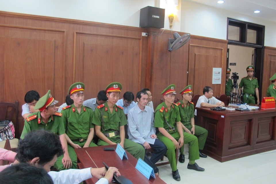 Các bị cáo tại phiên tòa (ngồi giữa và sau lưng lực lượng công an)