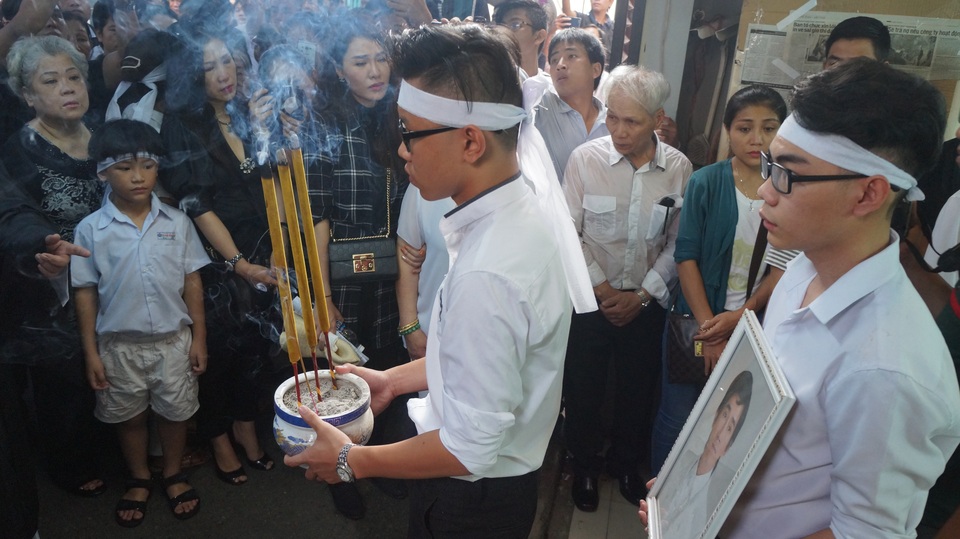 Hai con trai nuôi của ca sĩ Minh Thuận mang bát nhang và di ảnh của anh.