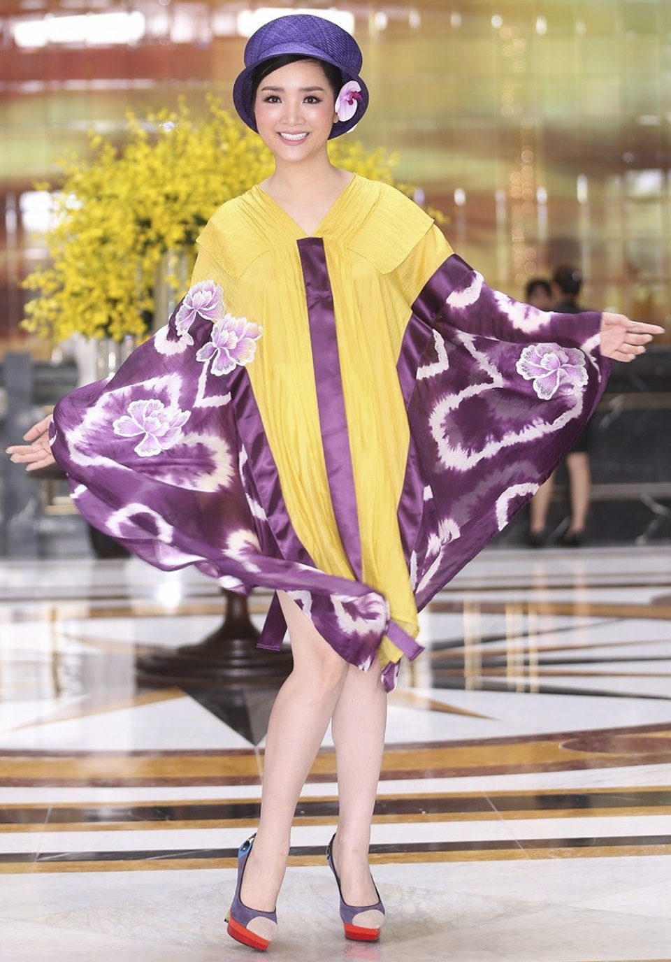 Giáng My sến sẩm khi khoác lên mình bộ áo choàng vàng-tím cùng hoạ tiết to bản cực kì lỗi mốt. Càng thất vọng hơn khi người đẹp kết hợp cùng nón trùm đầu và cài hoa, trang điểm nhợt nhạt thiếu sức sống.