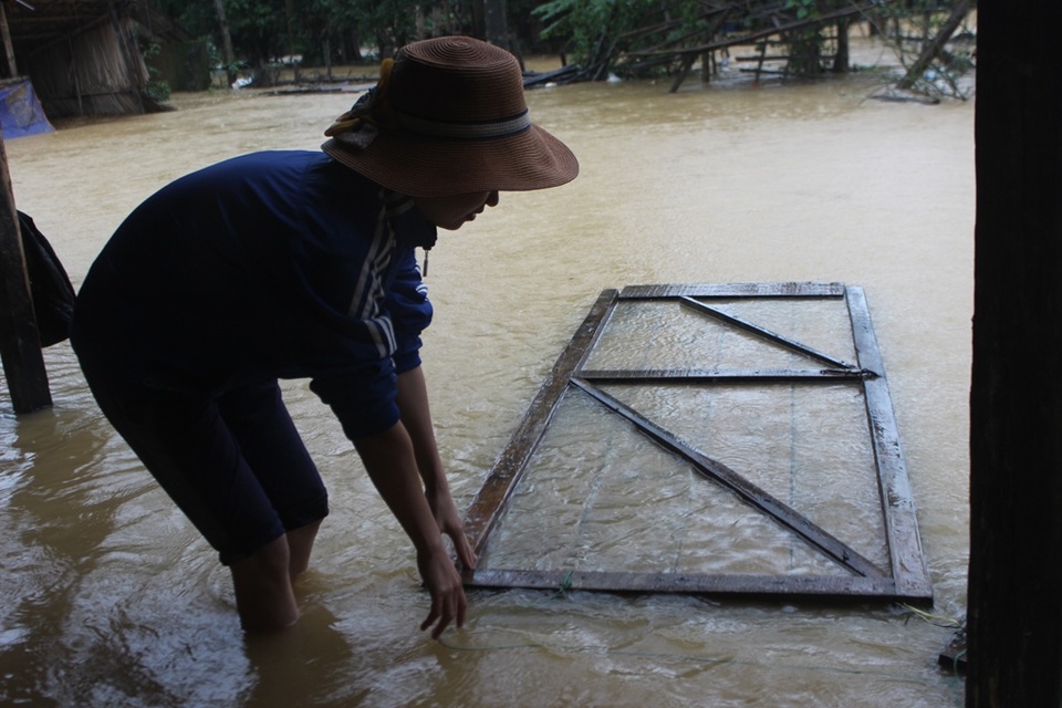 
Lũ lên trong đêm, nhiều đồ đạc nhà chị Nguyễn Thị Hiền bị trôi mất. Tranh thủ trời ngớt mưa chị Hiền ra vớt chiếc cửa bị nước lũ cuốn.
