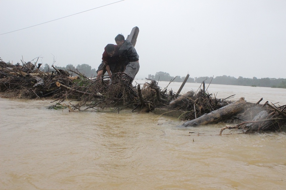 Một thanh gỗ lớn mắc ngay mé cầu được 2 thanh niên loay hoay nhổ lên