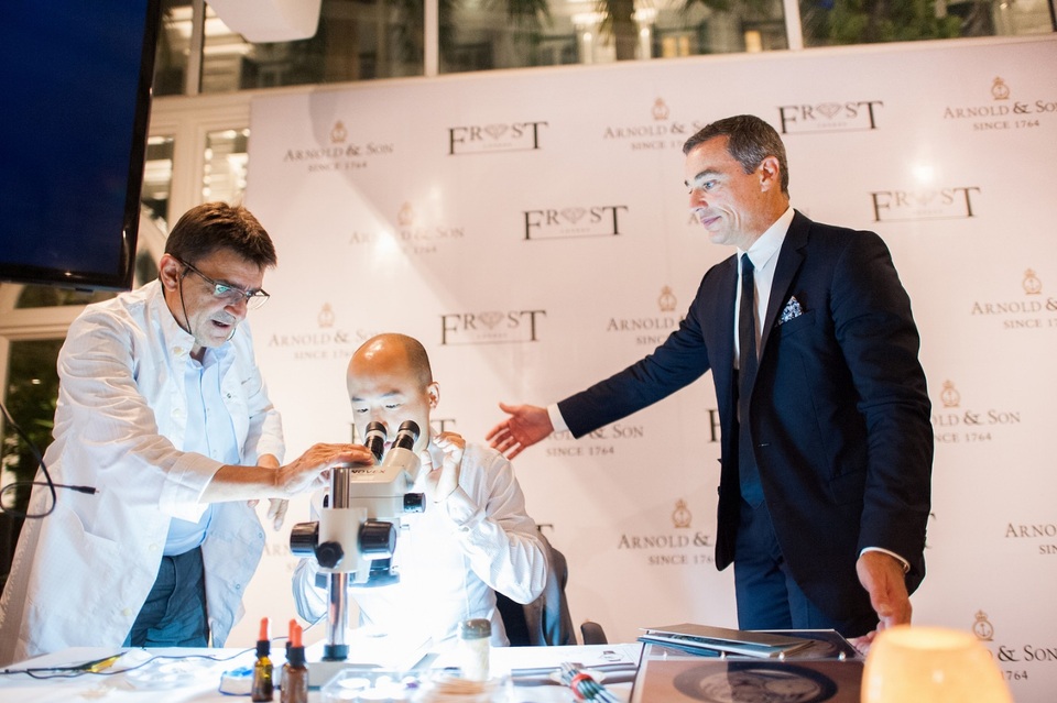 Nghệ nhân André Martinez hướng dẫn các vị khách ngắm nhìn kĩ hơn từng nét vẽ siêu nhỏ trên mặt đồng hồ qua thiết bị của mình.