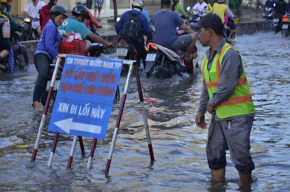 Công nhân thoát nước đứng điều tiết, hướng dẫn người dân di chuyển tránh điểm ngập sâu