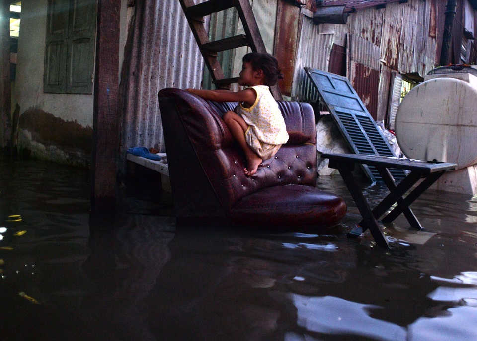 Triều cường tràn bờ gây ngập nhiều khu vực ở TPHCM - 11 Một em bé chơi đùa trên ghế do phía dưới đã bị ngập nước