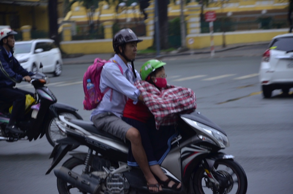 Một em bé được bố choàng áo phía trước để chắn gió lạnh khi chở đến trường