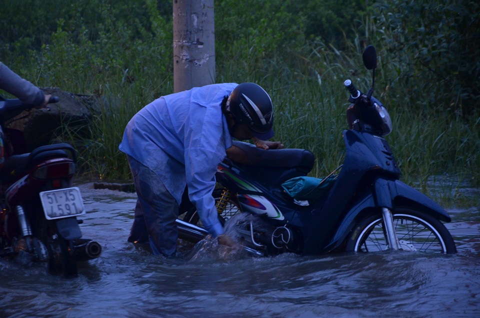 Tranh thủ triều cường, một người đàn ông đứng rửa xe giữa đường