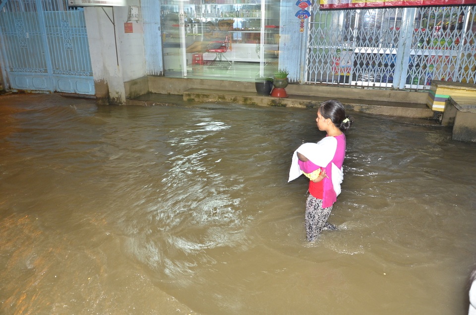Một phụ nữ bế con vượt qua điểm ngập