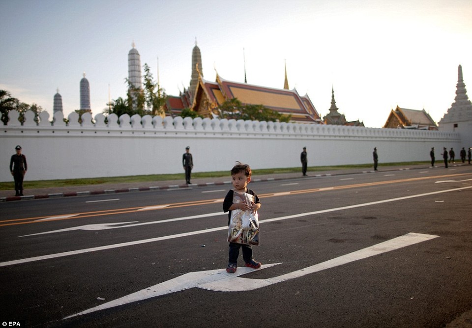 Khu đèn đỏ, các điểm vui chơi ở Thái Lan đìu hiu trong thời gian quốc tang - 10 Một bé trai người Thái ôm bức hình về các thành viên Hoàng gia