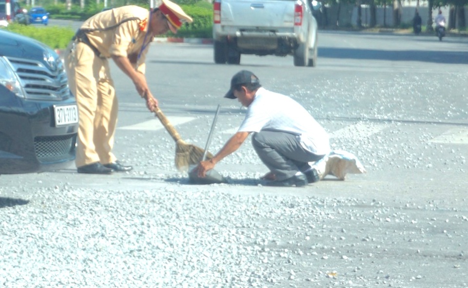 Trung úy Hưng cùng một người đi đường dọn số đá rơi vãi trên đường.