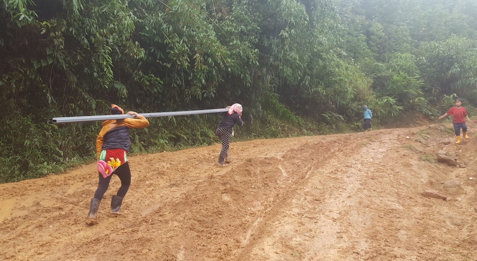 Gùi tôn, xà thép vượt dốc, leo đồi xây điểm trường Pà Khốm - 2 Đàn bà trong bản bê những thanh thép sắt lên dốc cao.