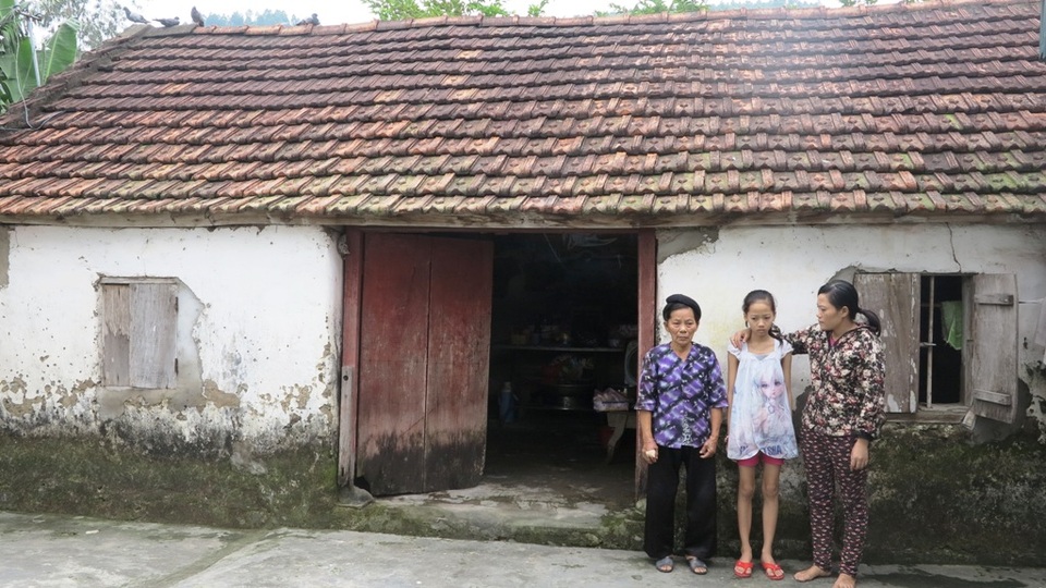 Ba mẹ con bà cháu bên căn nhà cũ nát.