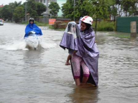Một bé học tiểu học cũng phải lội nước giúp mẹ đẩy xe khi xe của mẹ chết máy