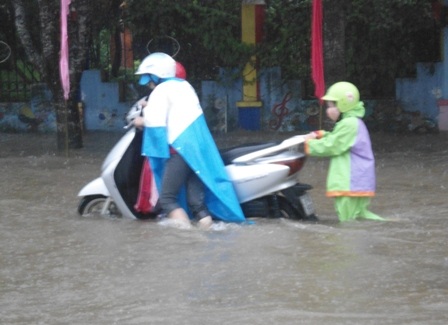 Một bé học tiểu học cũng phải lội nước giúp mẹ đẩy xe khi xe của mẹ chết máy