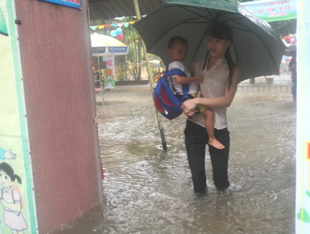 Một bé học tiểu học cũng phải lội nước giúp mẹ đẩy xe khi xe của mẹ chết máy