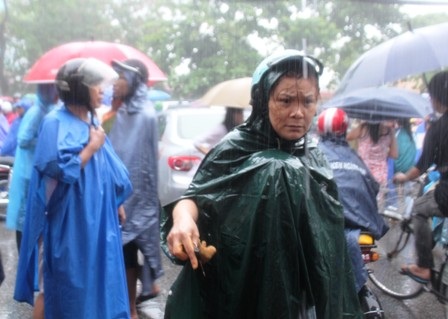 Một phụ huynh vất vả tìm con trong mưa lớn.