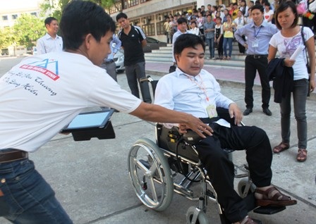 Thành viên CLB Mái ấm trường Vinh hướng dẫn Thành sử dụng xe lăn điện