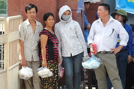 Sau khi nhận cơm, nhiều phụ huynh kiên nhẫn đứng đợi con ở cổng trường