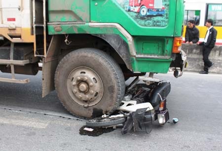 Chiếc xe máy nằm dưới bánh trước xe tải