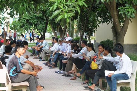 Phụ huynh, thí sinh ngồi hóng mát dưới tán cây xanh chờ làm thủ tục dự thi. (Ảnh: Nguyễn Duy)