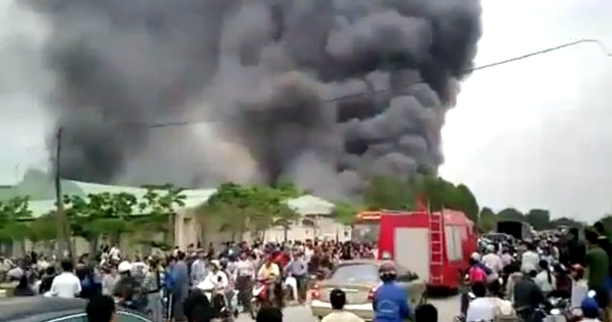 Lửa khói nghi ngút từ nhà máy, nhiều người dân hiếu kì đứng xem (ảnh cắt từ clip).