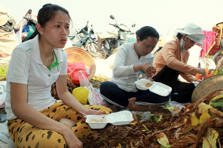 Nhộn nhịp xóm thuốc lào Sài Gòn - 12 Chị Nguyễn Thị Song Tuyền (31 tuổi, quận 12) tranh thủ giờ giải lao ăn vội hộp cơm chủ ụ thuốc mua cho.