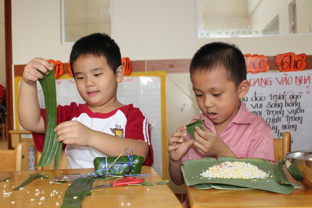 Bé tập gói bánh tét truyền thống