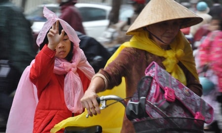 Mẹ đưa con hộp xôi, giục con bước nhanh vào lớp cho kịp giờ học.