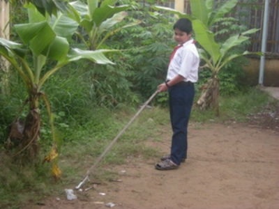 Em Hồ Lâm Hữu Luân sử dụng cây kẹp nhặt rác làm vệ sinh xung quanh trường