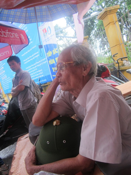 Ông ngồi đợi cháu ngoài cổng trường.