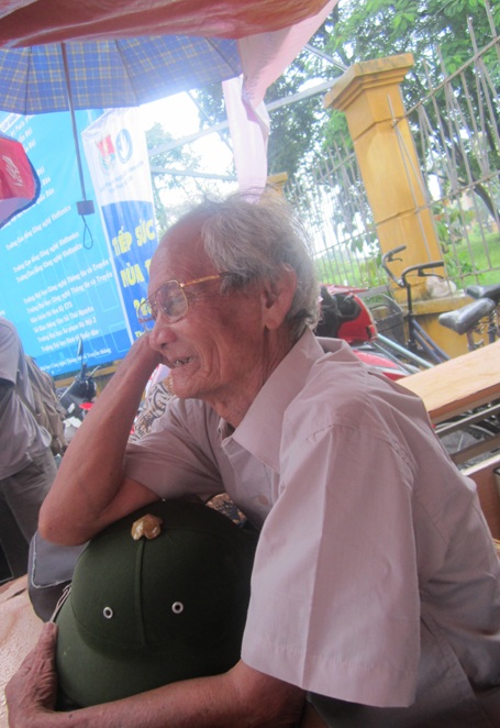 Ông ngồi đợi cháu ở ngoài cổng trường.