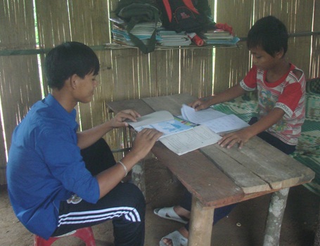 Dựng lều tìm chữ giữa đại ngàn - 1 Em Hồ Văn Côi (lớp 12) đang chỉ bài cho em Hồ Văn Kiệt (lớp 7) trước lúc đến trường.