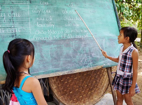 Ngỡ ngàng cô bé 8 tuổi dạy học miễn phí - 1 “Cô giáo nhí” Huỳnh Hoàng Anh đang giúp các bạn tập đọc, tập viết.