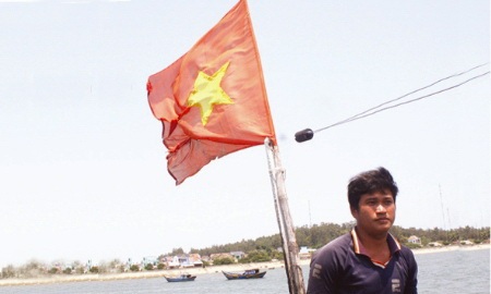 (Thuyền trưởng Bùi Văn Phải bên lá cờ Tổ quốc)