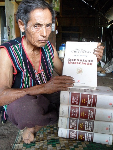 Nghệ nhân Điểu K’lung (71 tuổi, ở buôn Tul A, xã Ea Wer, Buôn Đôn, Đắk Lắk) bên bộ Sử thi Mơ Nông.