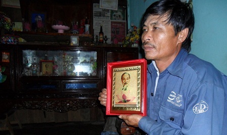 Anh Lê Văn Hiệu bên bức ảnh Bác Hồ do Phó Chủ tịch nước Nguyễn Thị Doan tặng.